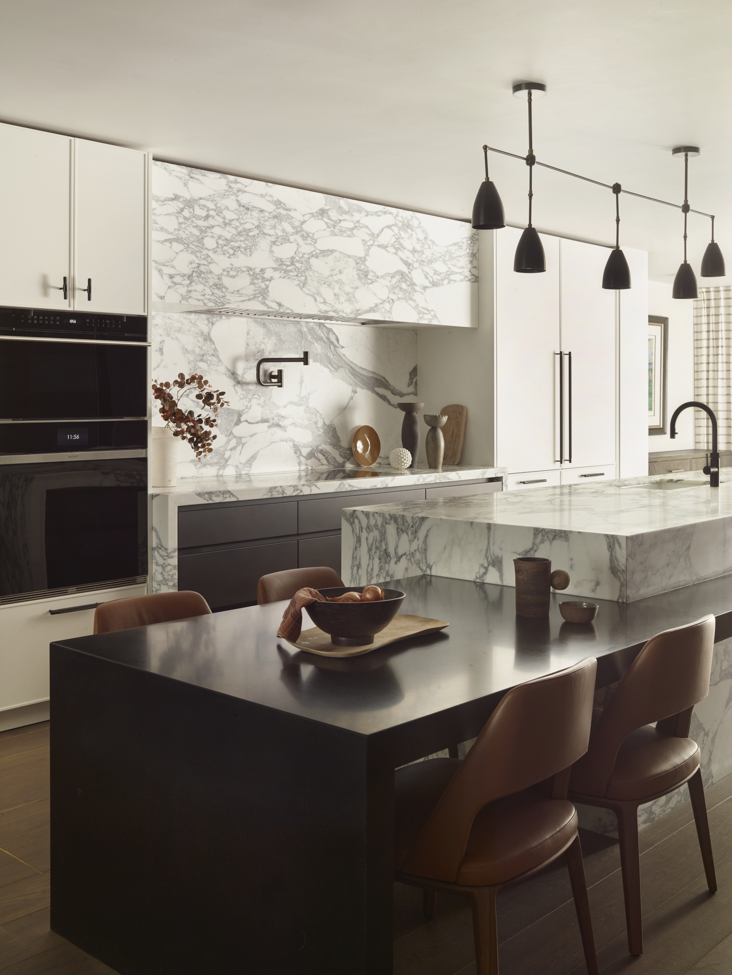 modern kitchen with marble island and attached seating area, and tall cabinets