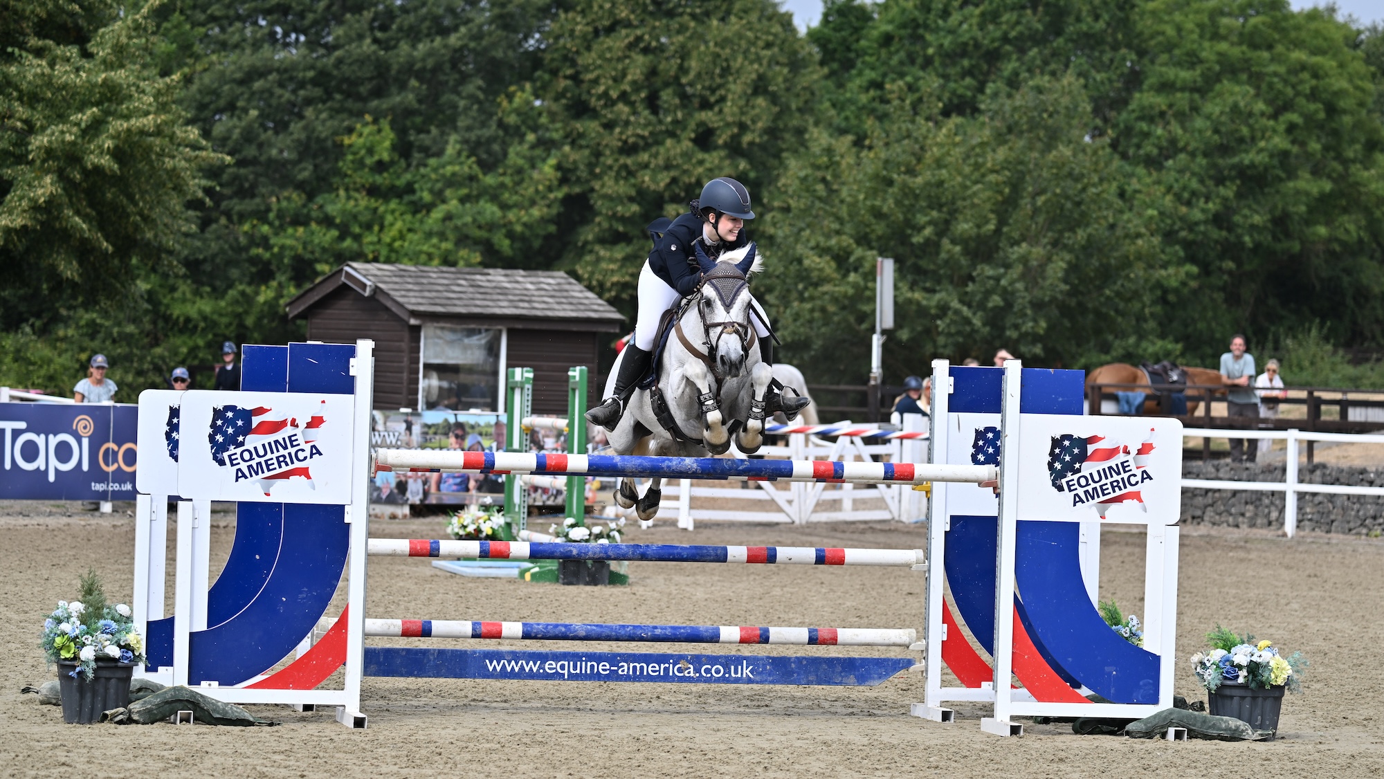 A young rider and a grey pony jumping a big oxer