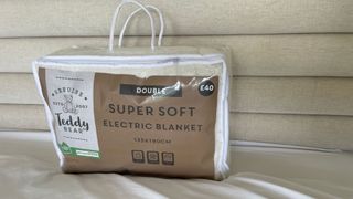 Dunelm Teddy Electric Blanket in its bag on a bed