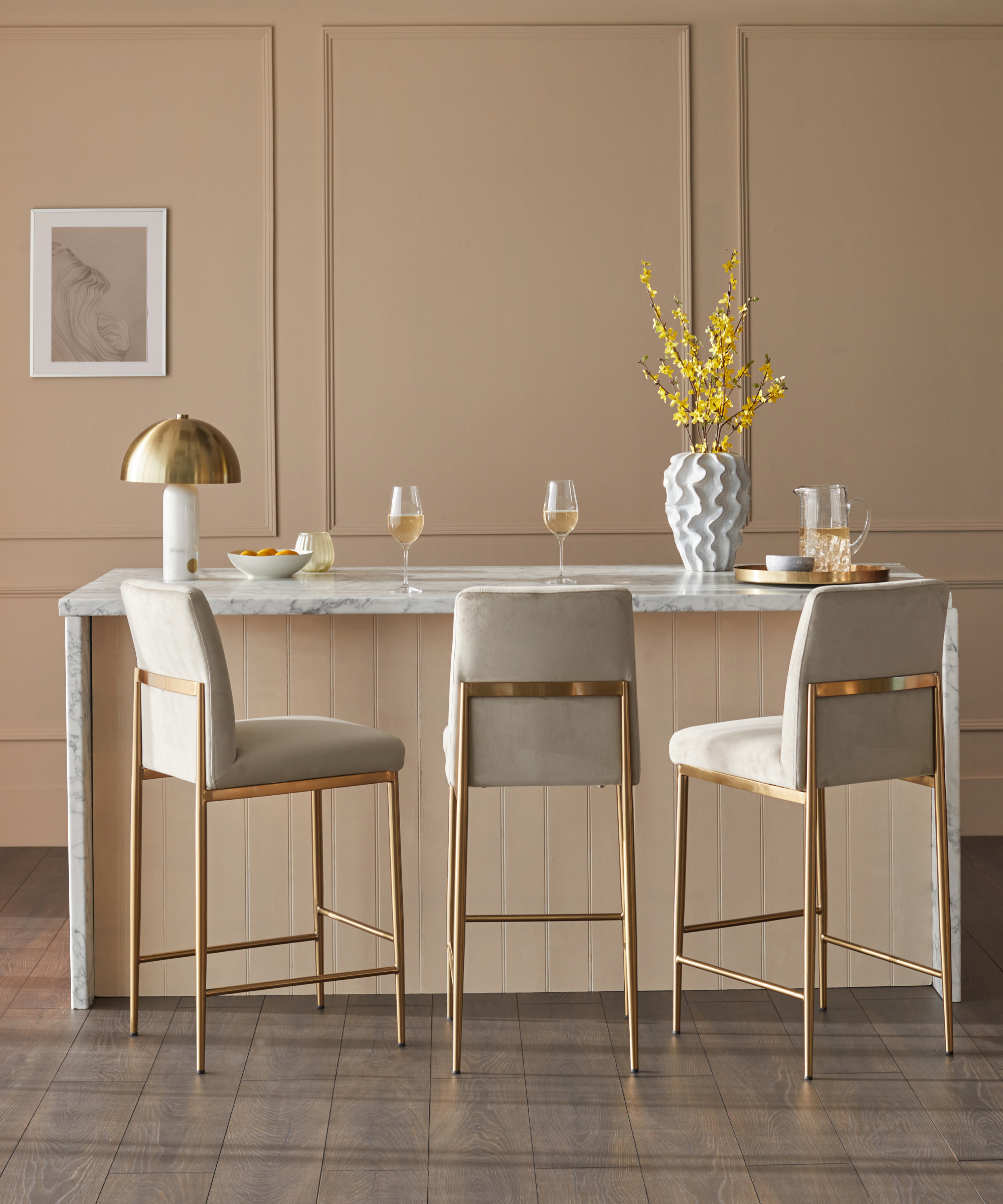 kitchen island with champagne coloured wood panelled walls, cream and gold bar stools