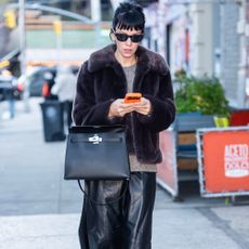 Lily Allen wears Hush fur jacket with a grey jumper a black leather skirt black lug-sole boots and a black Hermes bag and black sunglasses.