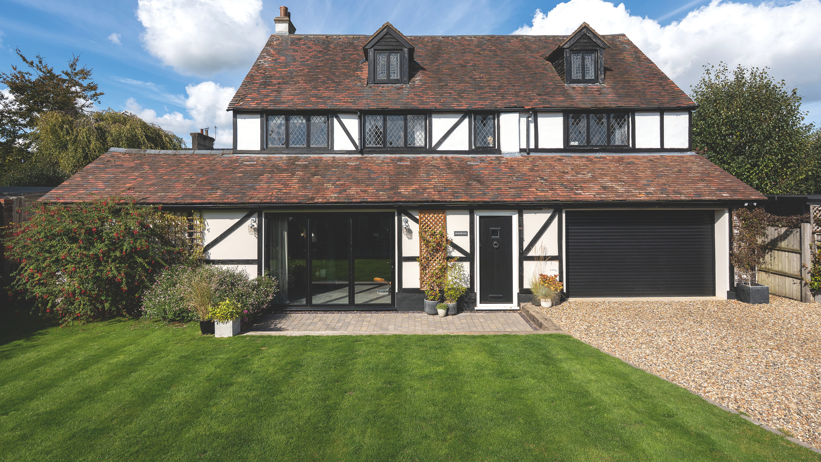 Lush green lawn at the front of a detached tudor-style property.