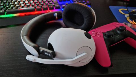 Sony Inzone H7 Review image with headset lying horizontal on a desk, next to a Pink Dualsense controller