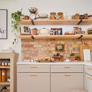 Warm toned kitchen colour scheme with white worktops decorated with baked treats and trainkets