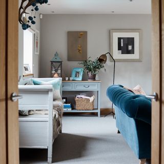A living room with a grey carpet and a blue velvet sofa