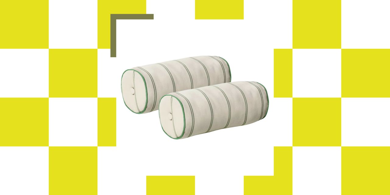 Cream outdoor bolster pillows with green stripes and button tufting against a colorful checkered background.