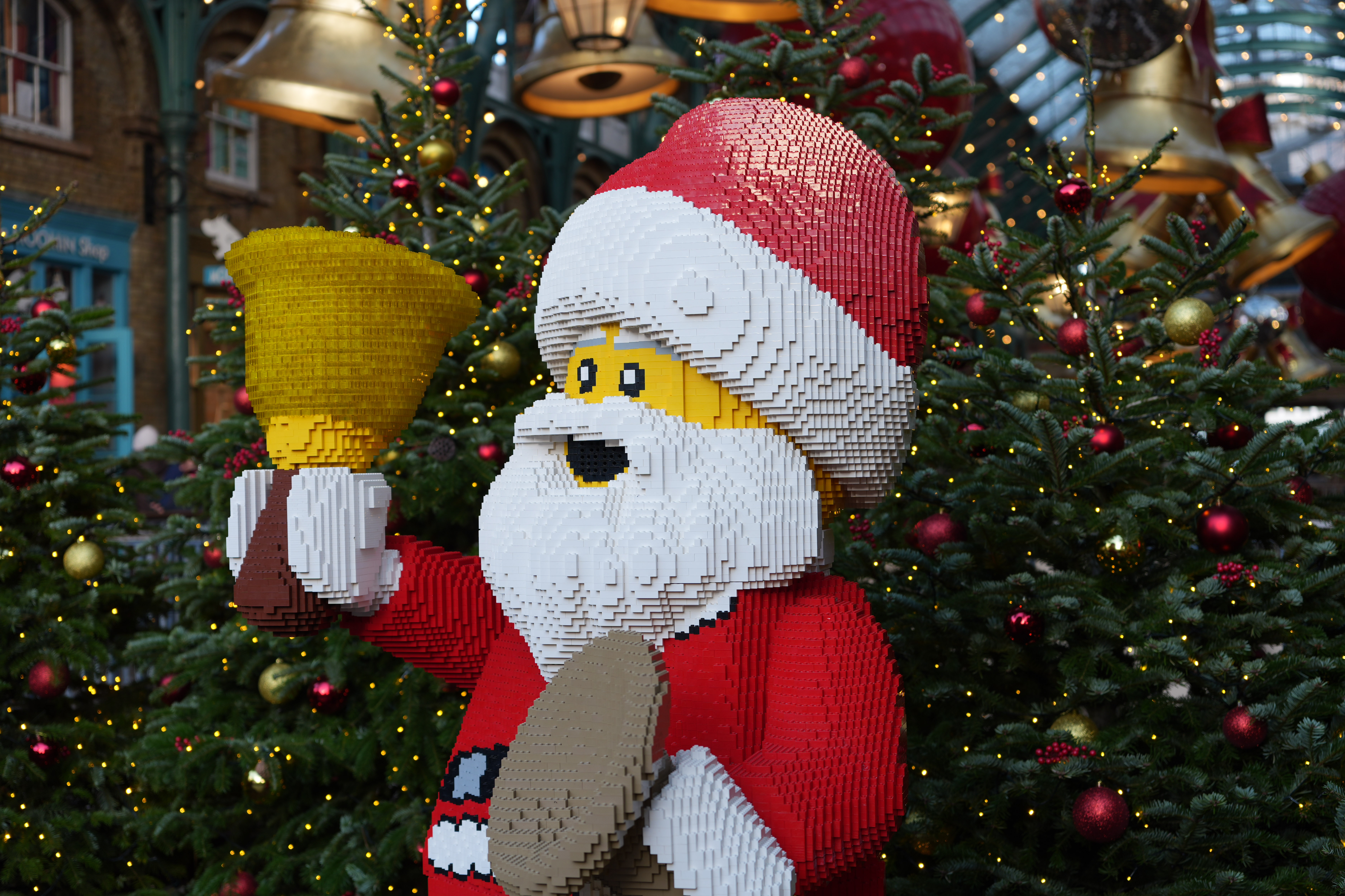 A Lego statue of Santa Claus in front of a Christmas tree