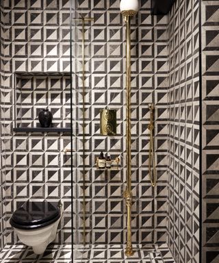 black bathroom ideas, black and white shower room with WC, brass fixtures and fittings, black shelves, graphic wall and floor tiles