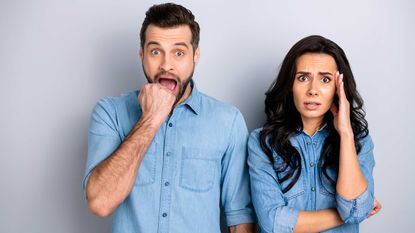 A man and a woman cringe with disbelief.