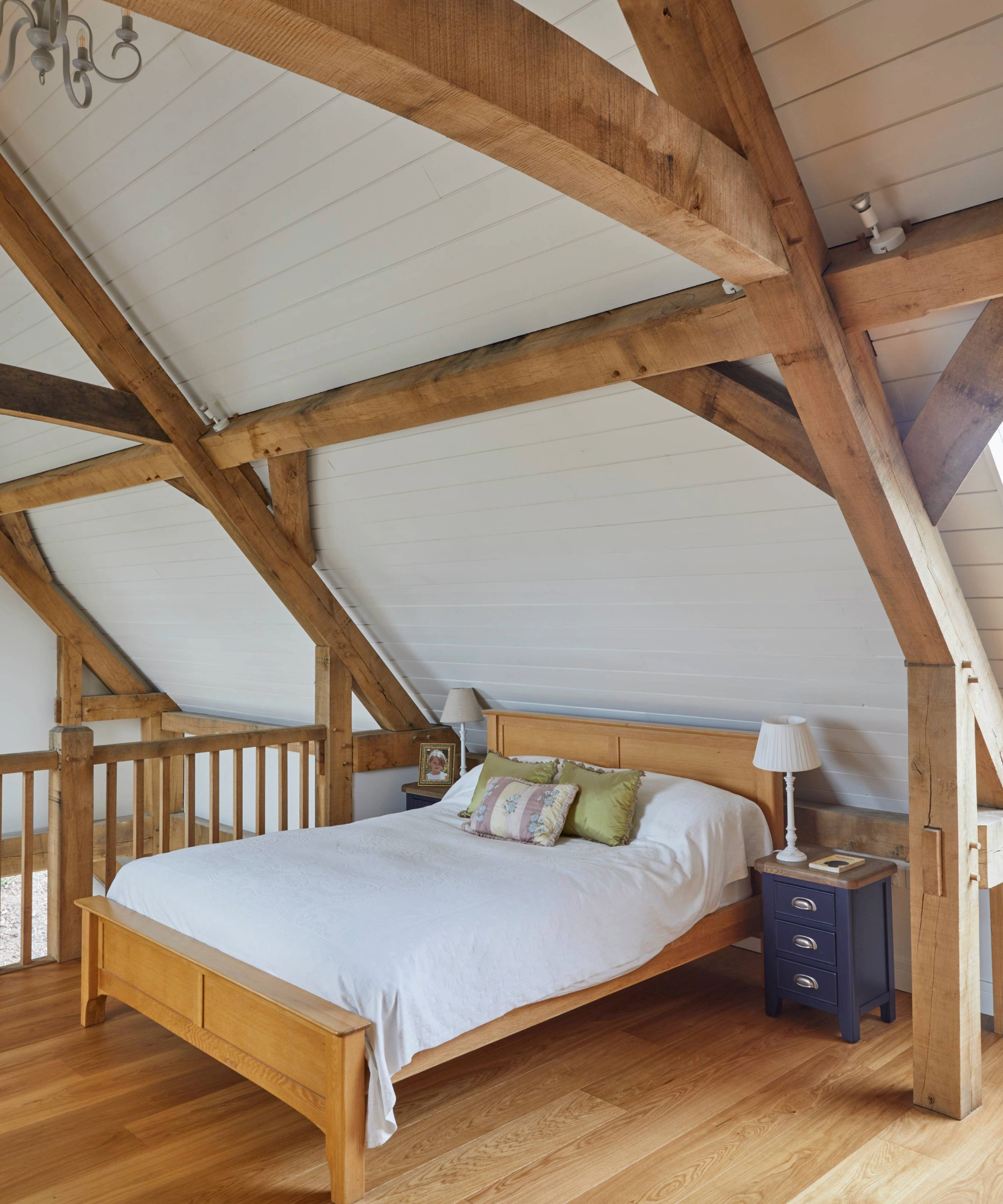 Bedroom on mezzanine floor with wooden beams and flooring