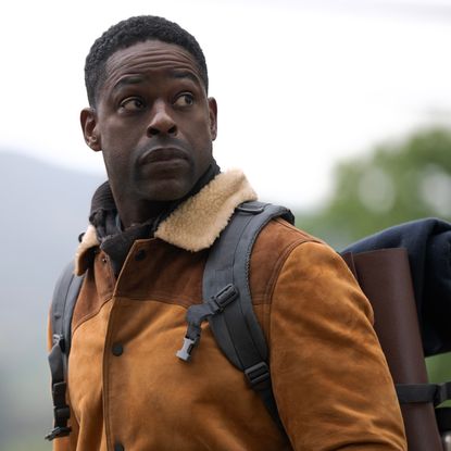 sterling k brown as xavier wearing an orange jacket and carrying camping gear on a mountain in paradise season 2
