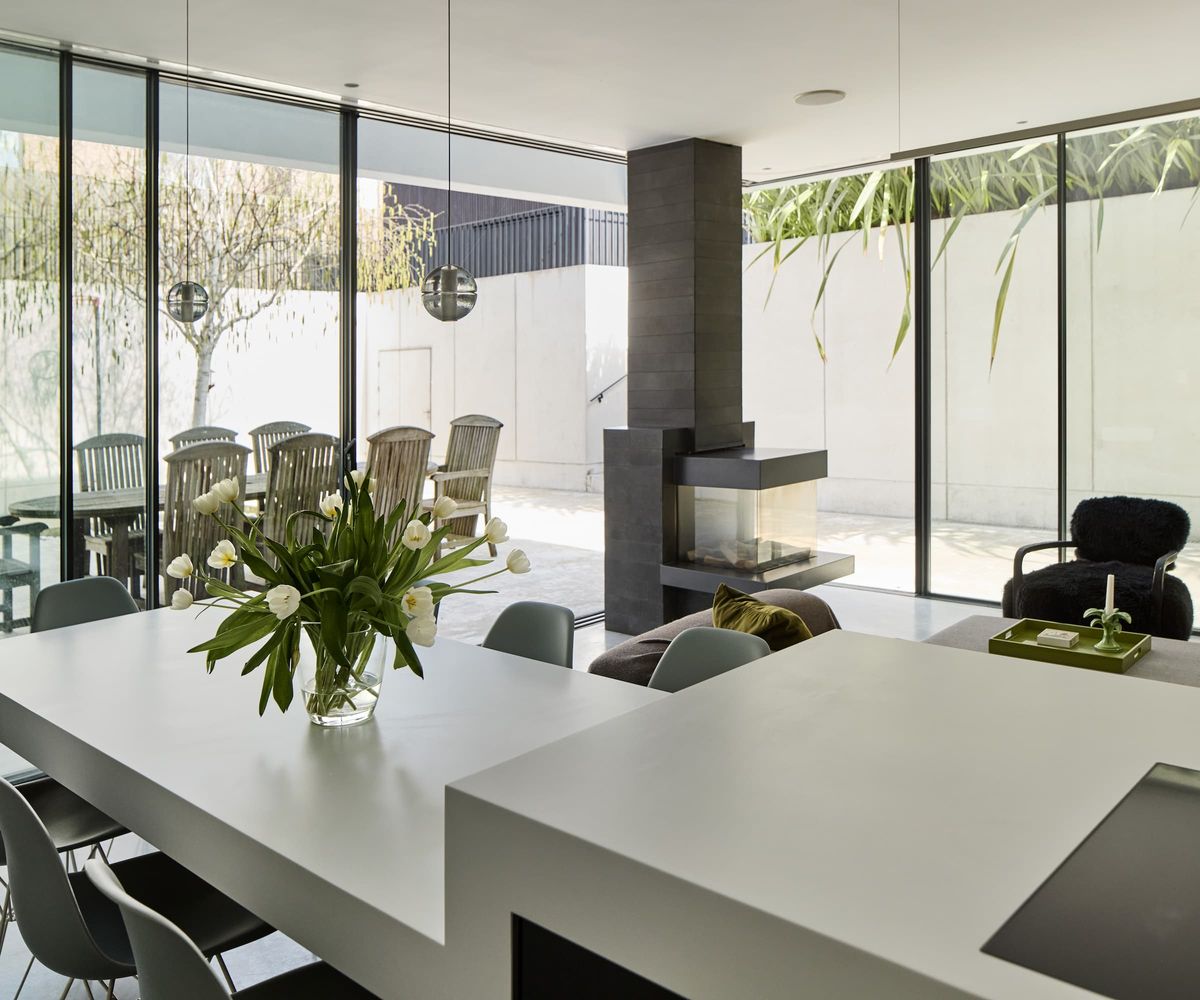 A kitchen dining area with a layered kitchen island with a grey worktop and a black woodburner