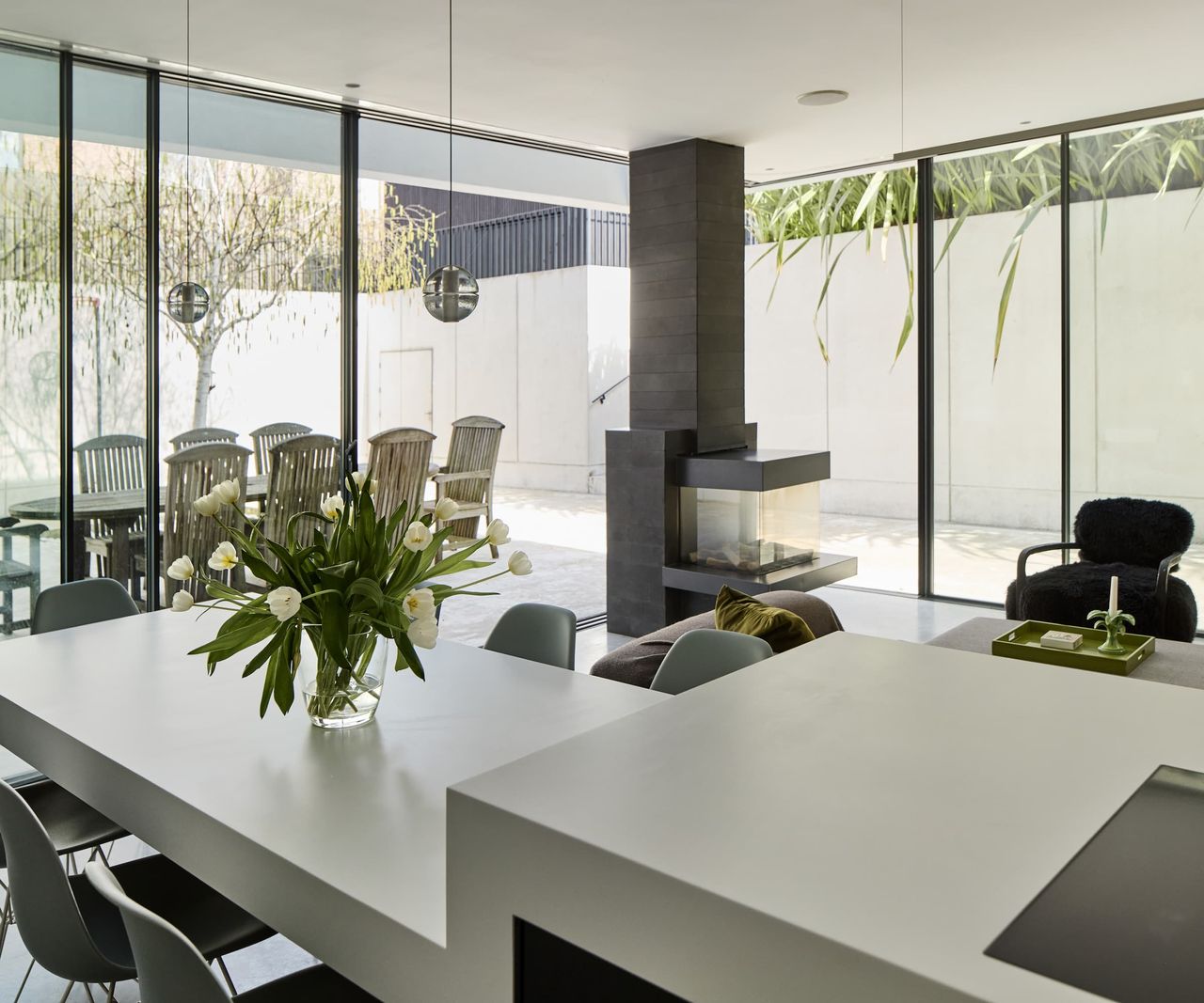 A kitchen dining area with a layered kitchen island with a grey worktop and a black woodburner