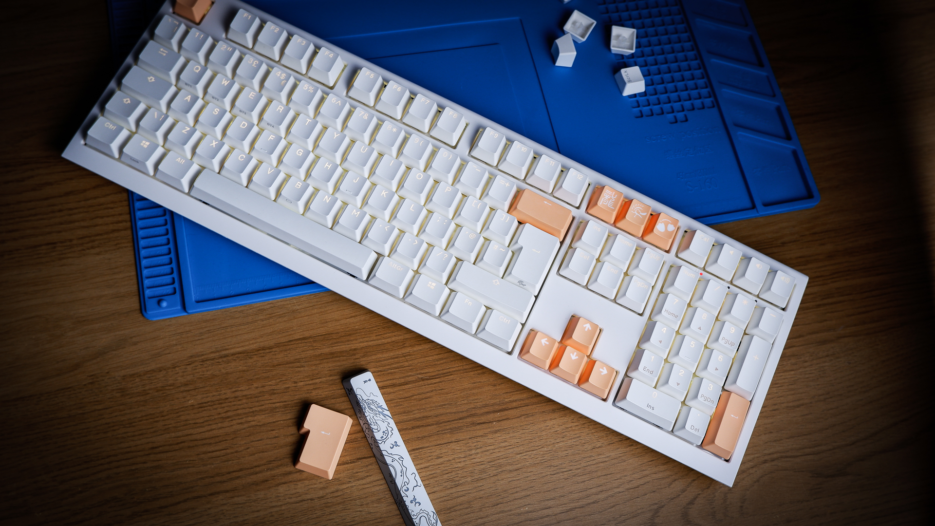 The Ducky One X induction gaming keyboard on a blue mat on a desk, with keycaps removed.