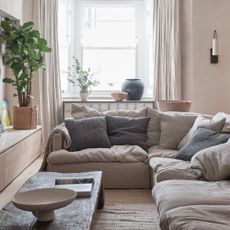 A neutral beige living room with a corner sofa and a rustic wooden coffee table