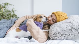 lady with hat on in bed with dog