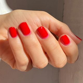 Short red nails with a hint of pink by the cuticle