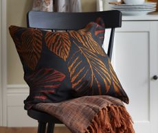 A chair with a black and orange cushion on it with a leaf pattern
