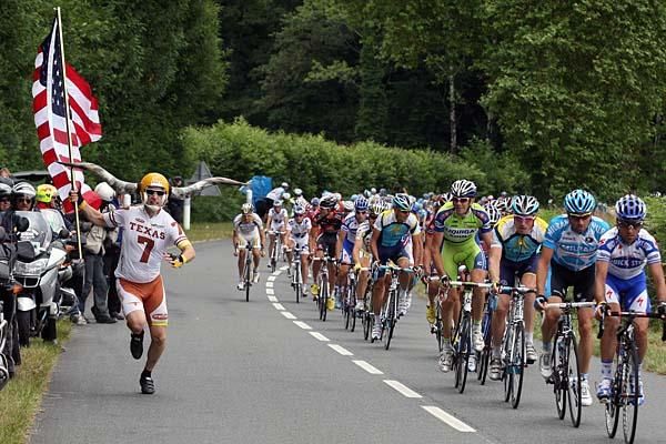 A fan from Texas cheers on passing racers.