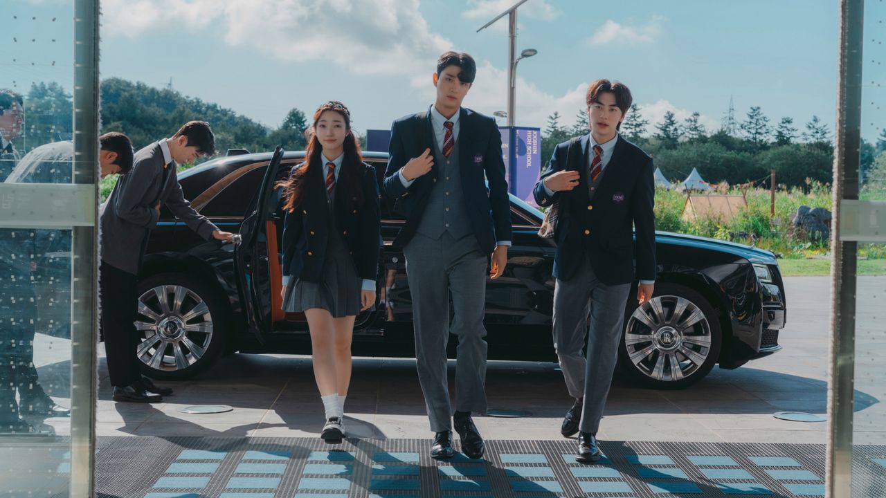 three students in private school uniforms enter a school, with a Rolls Royce sitting behind them and chauffeurs bowing, in Netflix k-drama &#039;Hierarchy&#039;