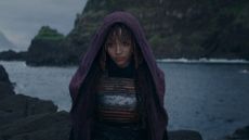 A hooded Mae stands on a shoreline in Star Wars: The Acolyte