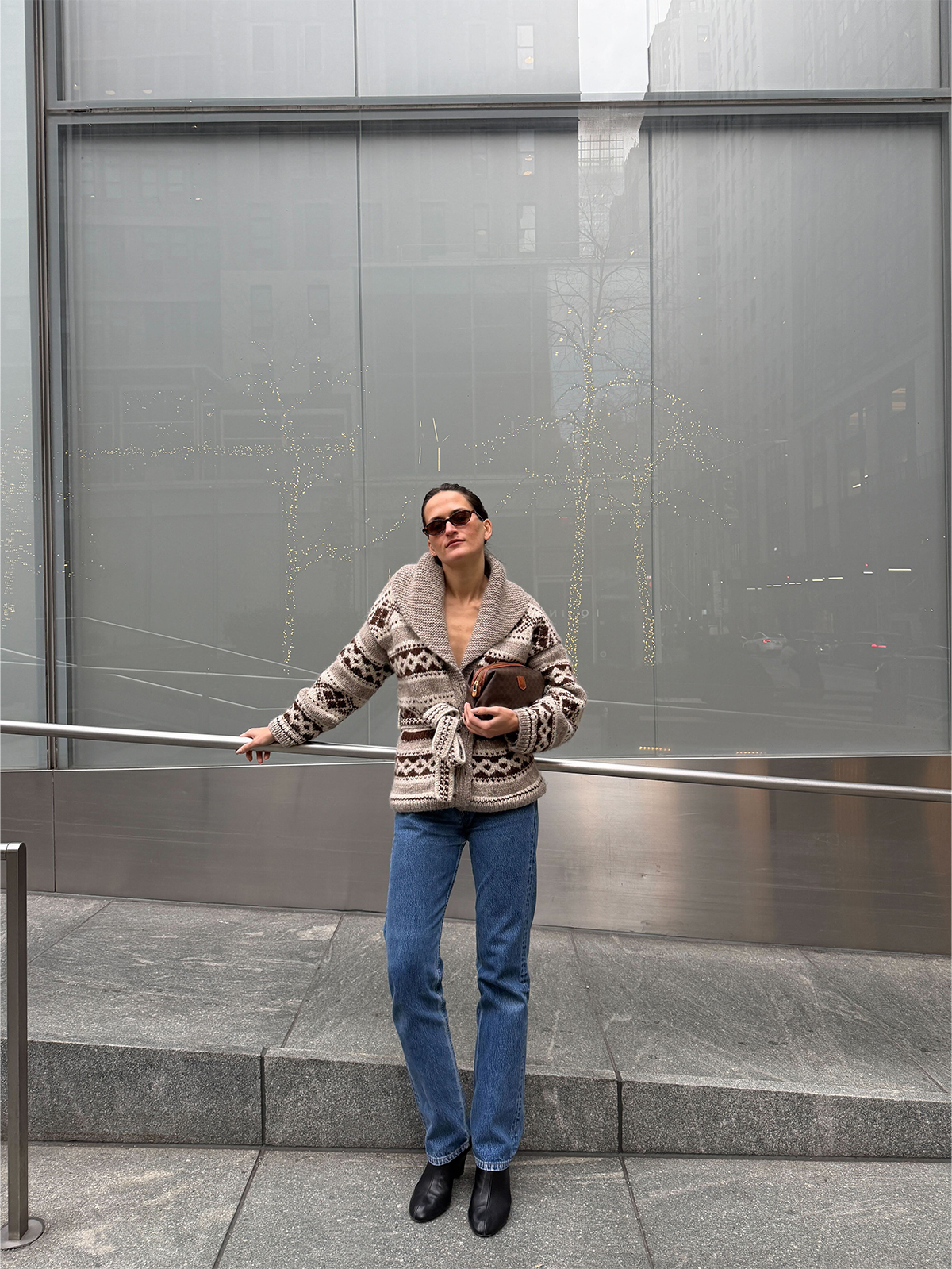 Eliza Huber wearing the Doen Hale Cardigan with jeans and a brown Celine clutch bag.