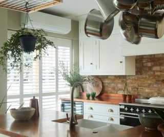 white Shaker kitchen with hanging saucepans and white full height window shutters