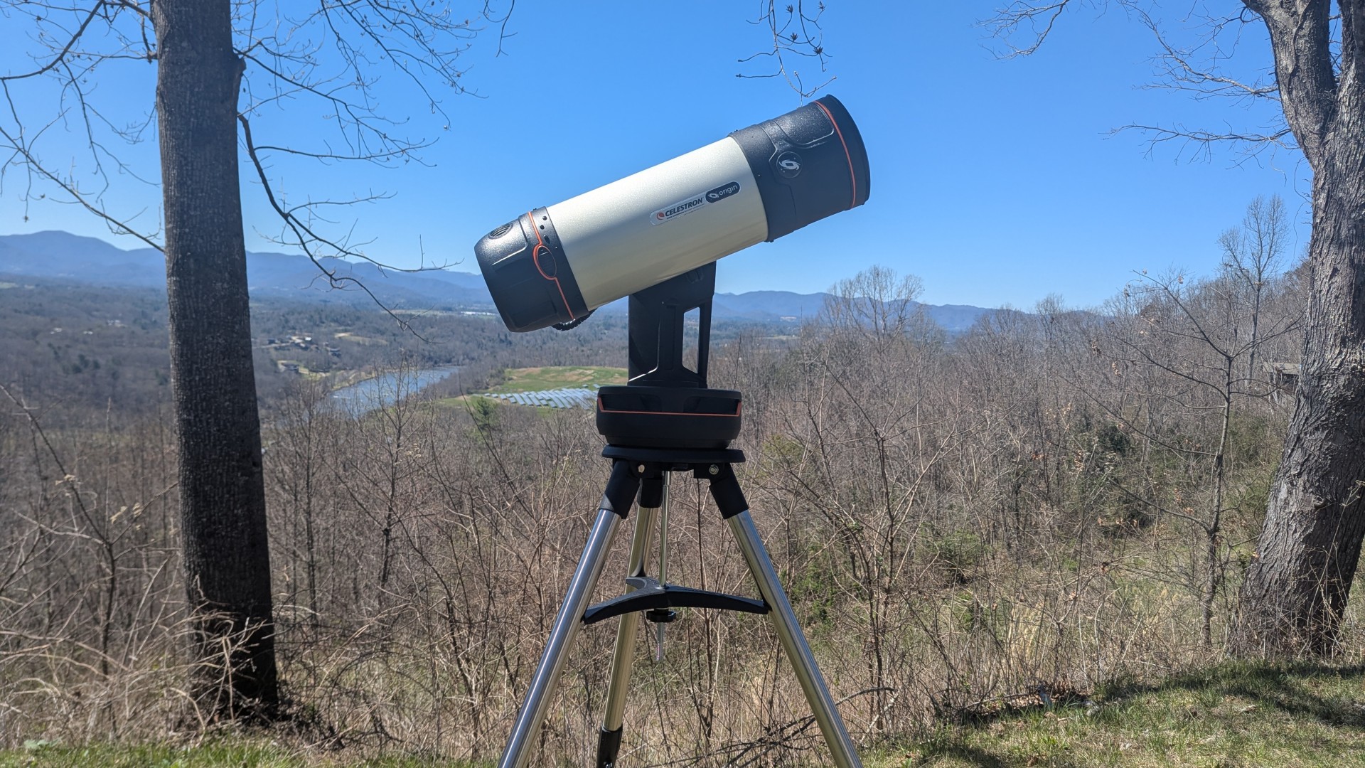 a white telescope on a grassy mountaintop under a clear blue sky