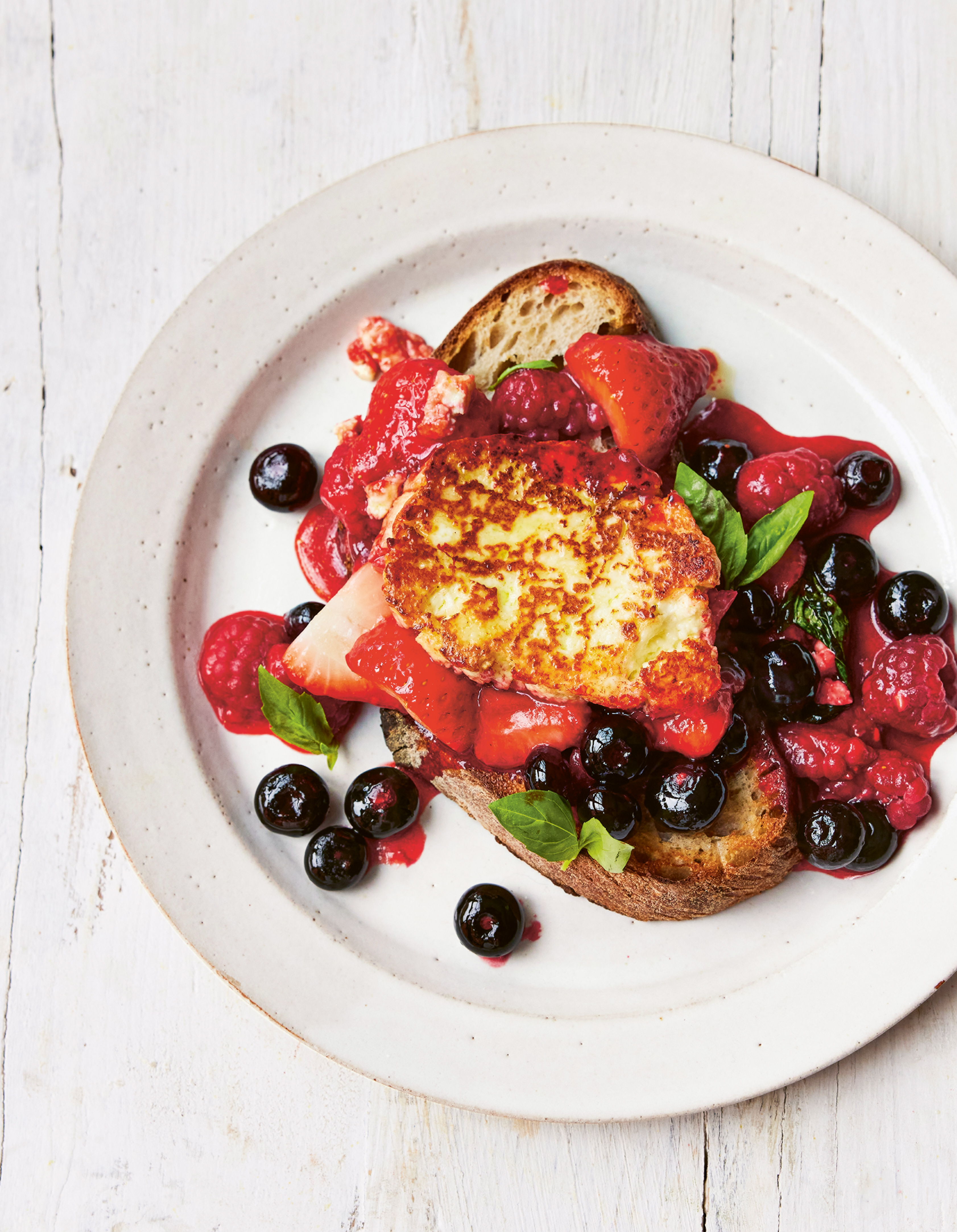 A plate of toast with berries and halloumi cheese