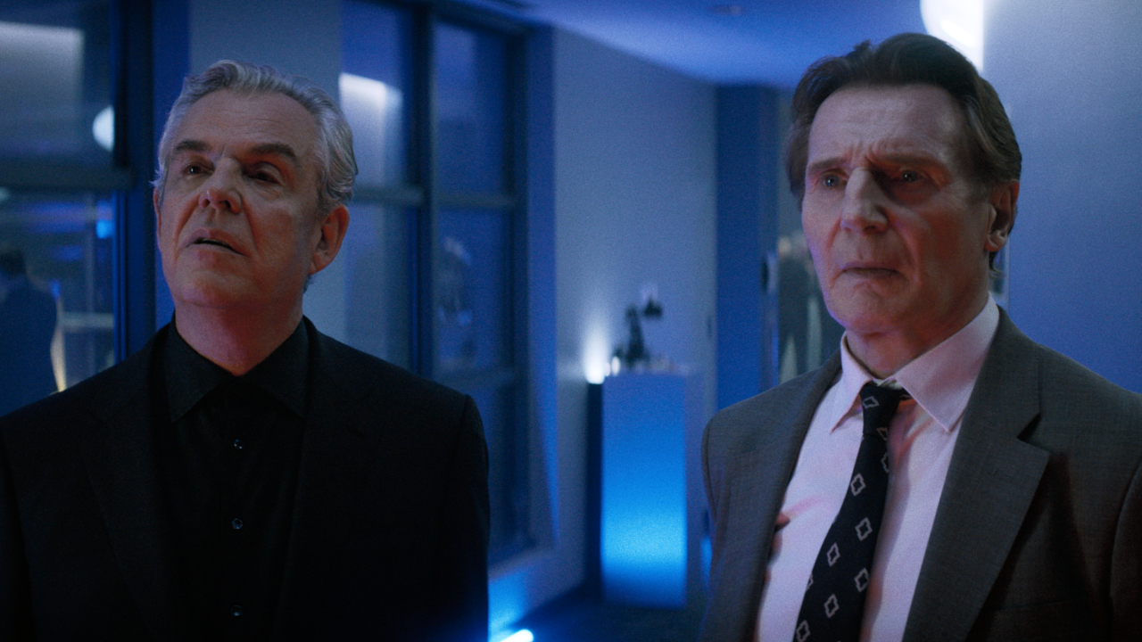 Danny Huston and Liam Neeson looking together at something off camera in The Naked Gun 2025. 