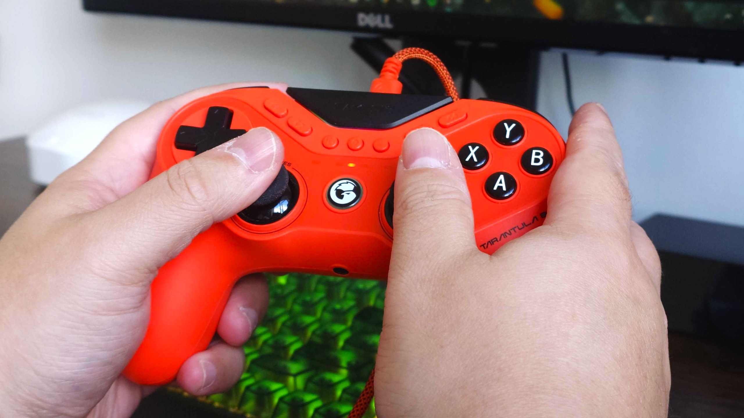 The GameSir Tarantula 8K controller being held in two hands in front of a keyboard with green glowing backlight 