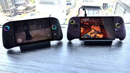 Two handheld gaming devices (Acer Predator Atlas 8 and MSI Claw 8 EX AI+) on a table, showing different video games with a cityscape in the background.