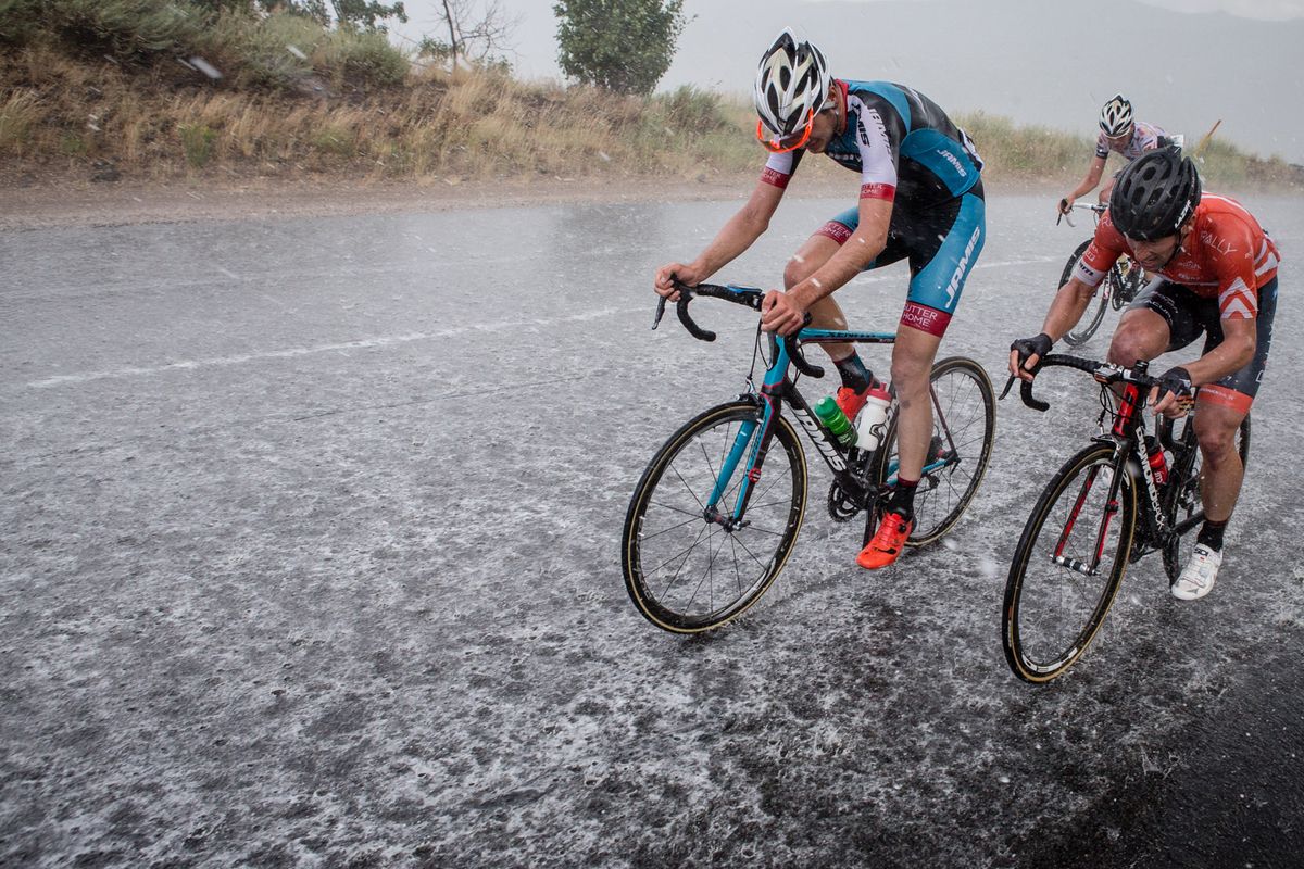 Water washes over the road as riders hit the climb