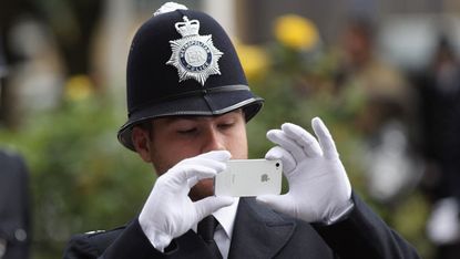 A Metropolitan police officer uses a smart phone