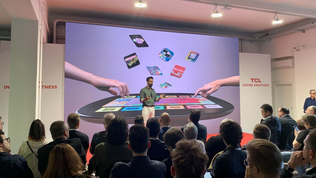 TCL Telly Table image onstage, with a man talking in front of it, at Milan Design Week