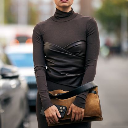 fashion week attendee wearing brown dress and carrying brown suede bag