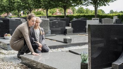 A young widow and her daughter visit a grave.