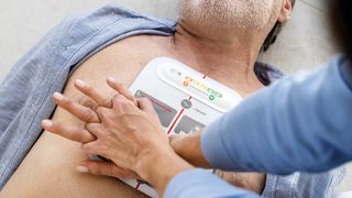 Person giving CPR to a man. The Beurer LifePad is on his chest, the person’s hands is pressing on the pad