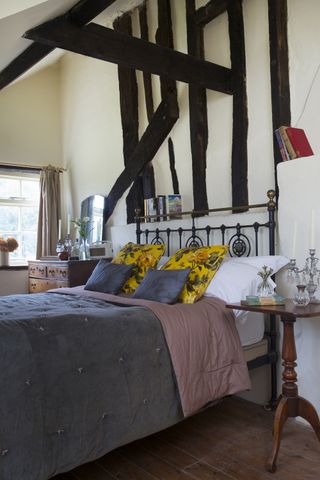 iron bed in farmhouse with windows and beamed walls