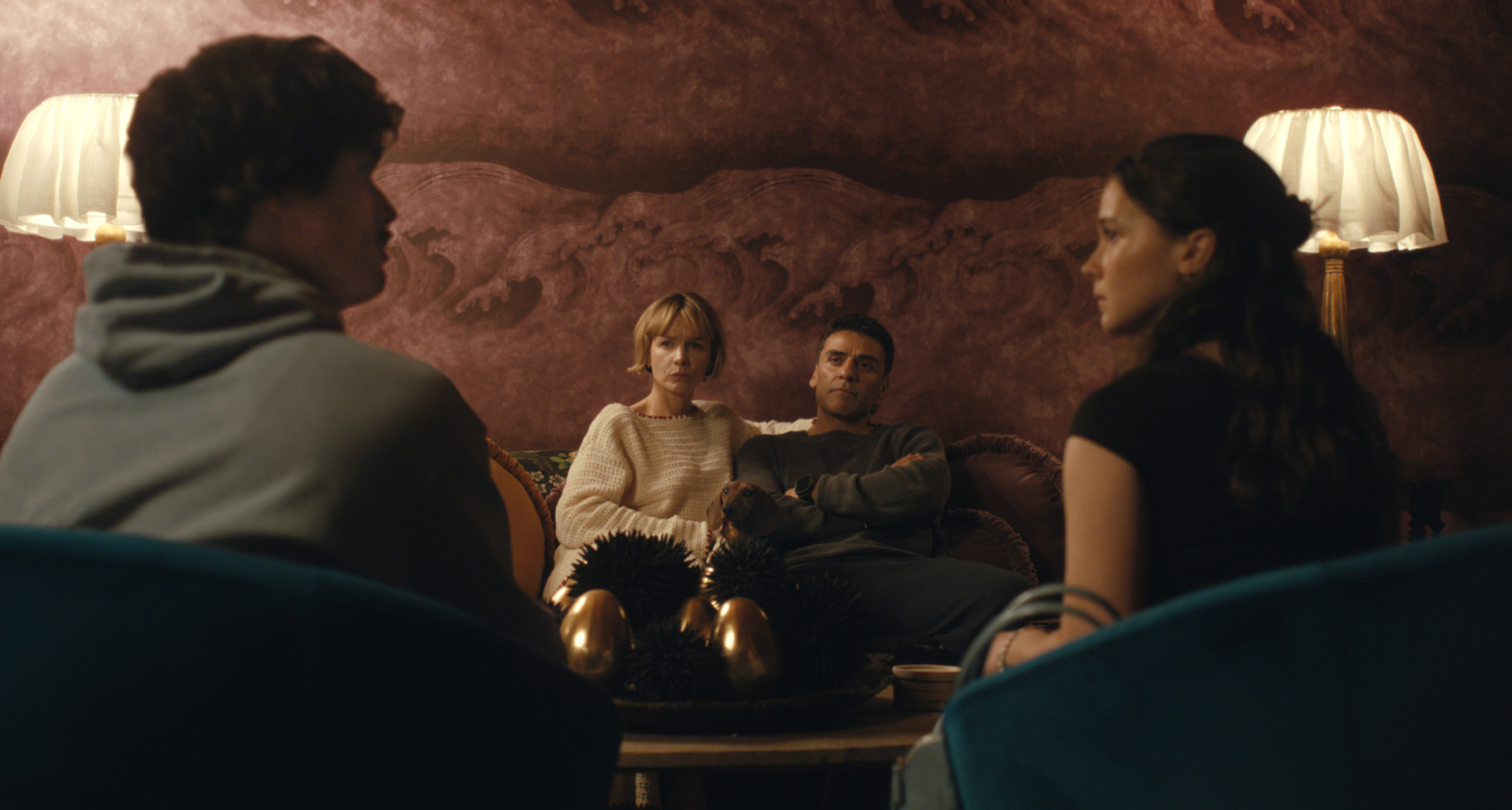 charles melton and cailee spaeny as a couple looking at each other sitting across from another couple played by carey mulligan and oscar isaac having a tense conversation in beef season 2