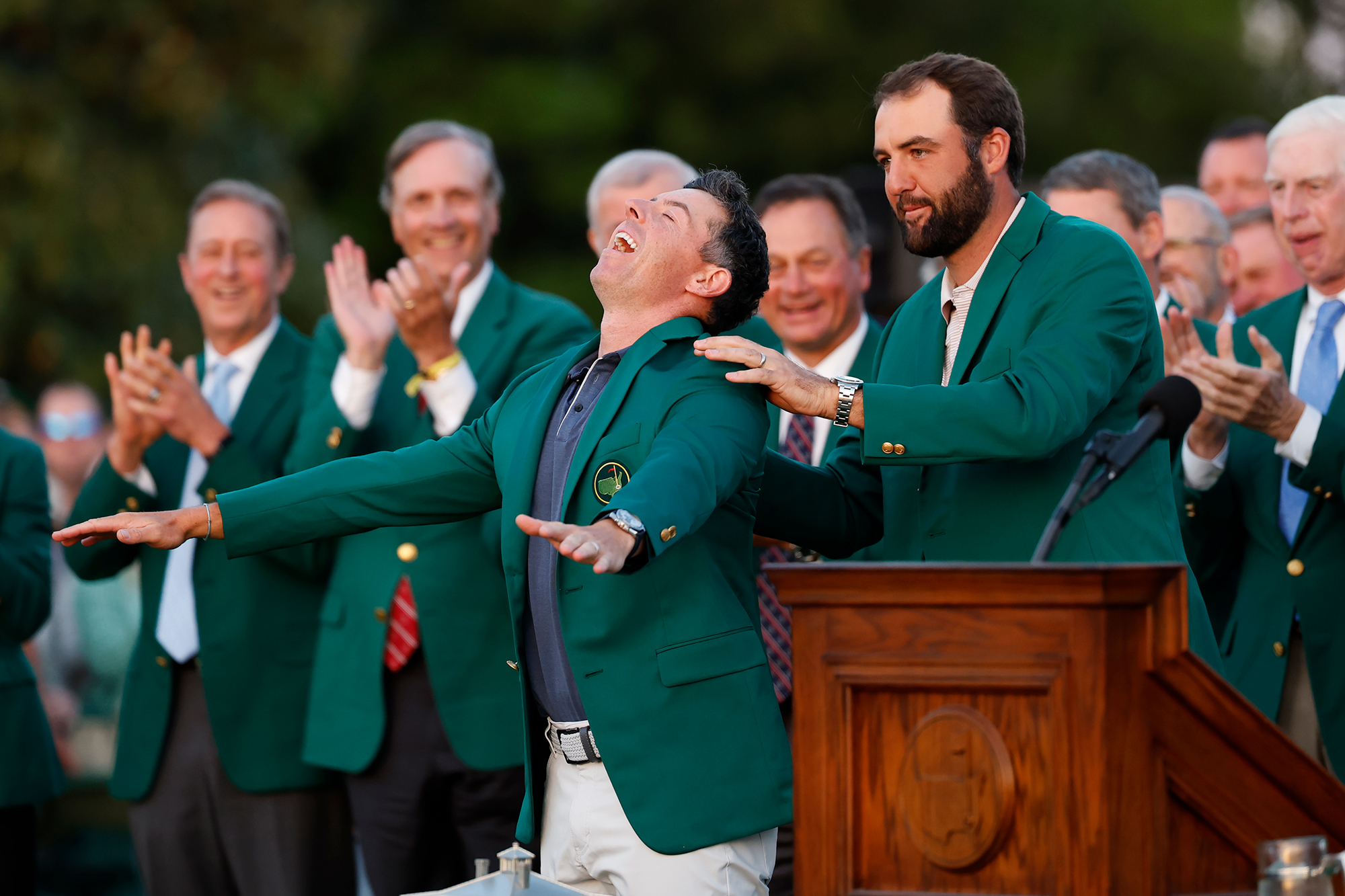 Scottie Scheffler placing the Green Jacket onto Rory McIlroy as the Northern Irishman completes the Career Grand Slam