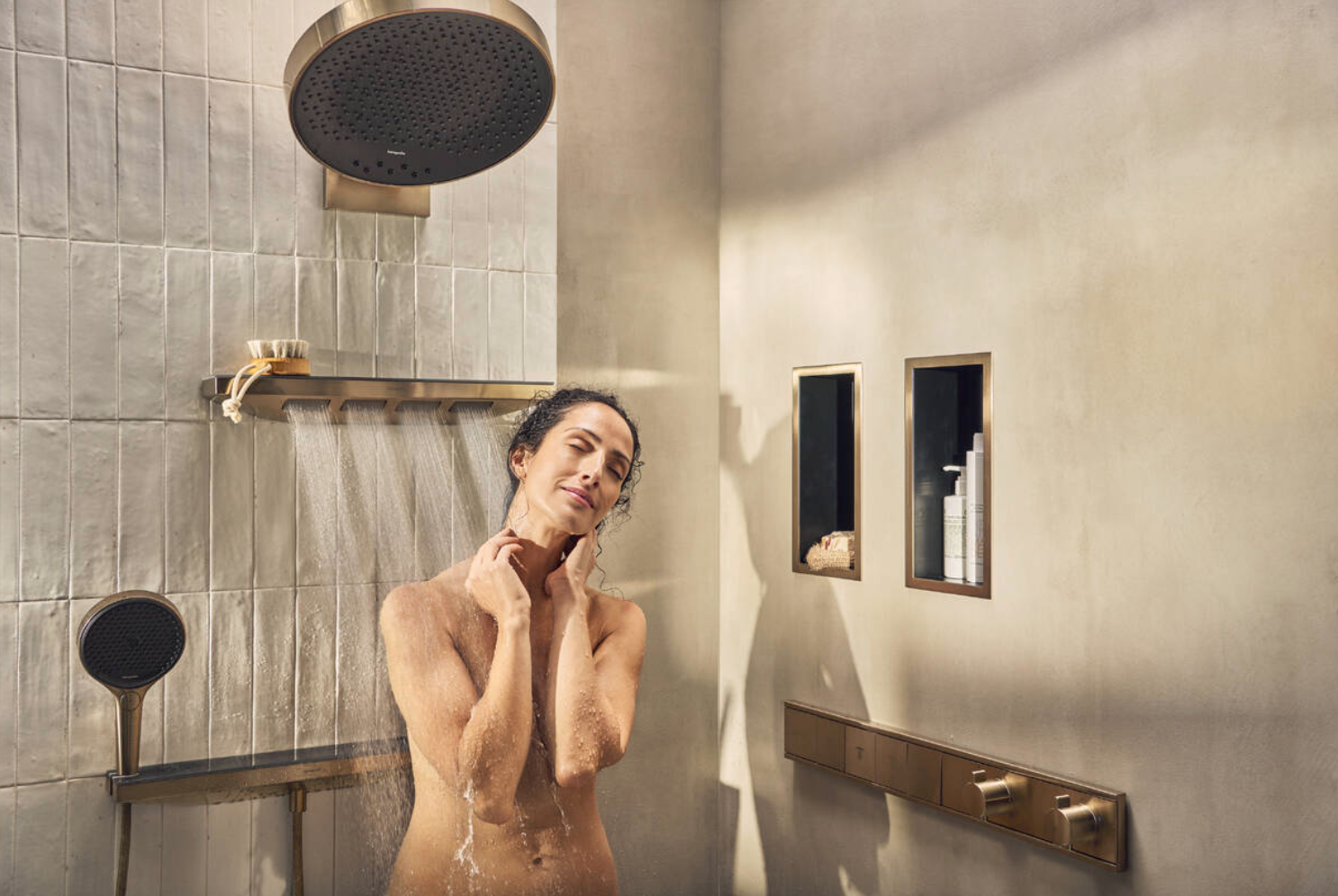 model stands in shower with beige tiles and gold tapware