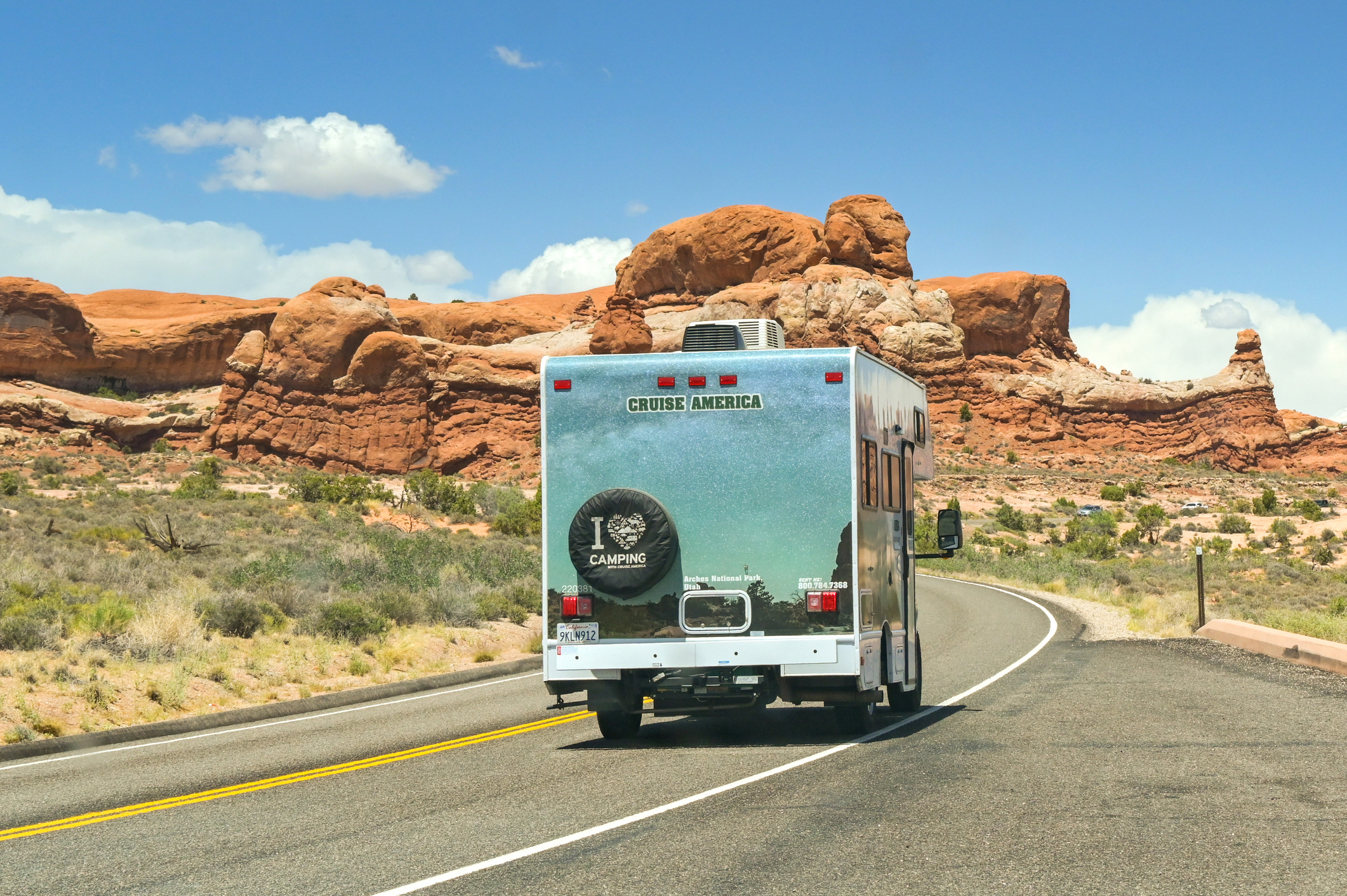 Moab, Utah, USA - 25 May 2025: Camper van driving through spectacular landscape scenery in the Arches National Park in Moab