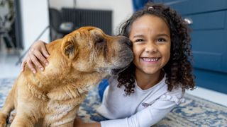 Young girl lying on the floor hugging her dog