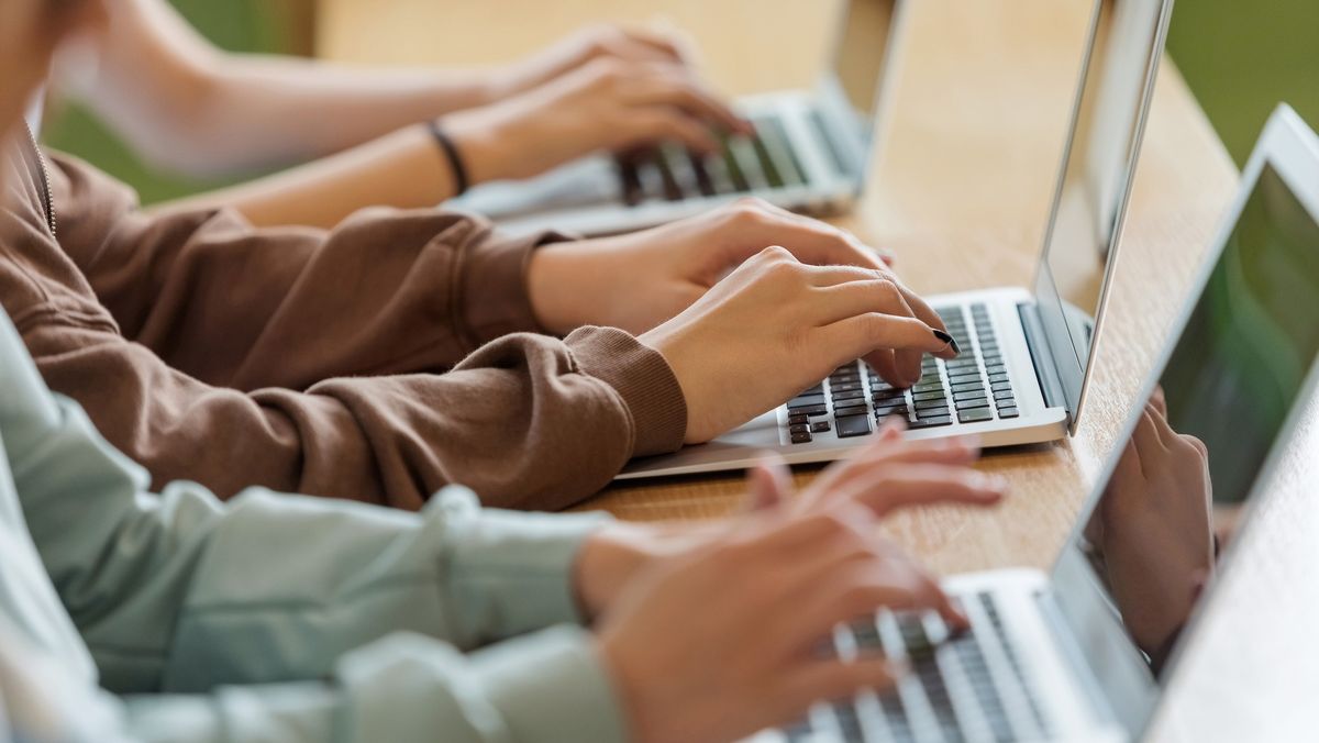 A close-up shot of students&#039; hands working on laptops, to represent digital literacy among young people.