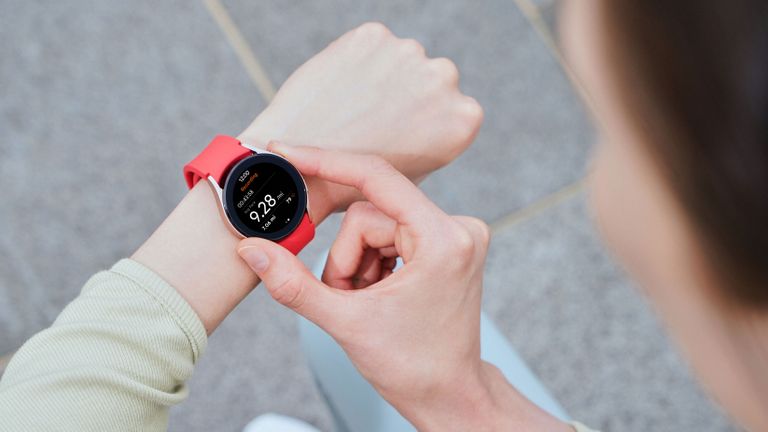 Samsung Galaxy Watch 4 with red strap on an adult woman's wrist