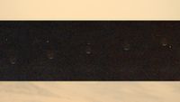 a dot of light disappears behind a crescent of light on a grey background