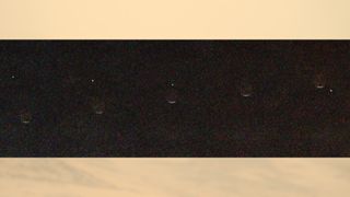 a dot of light disappears behind a crescent of light on a grey background