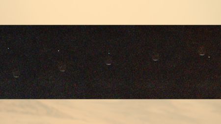 a dot of light disappears behind a crescent of light on a grey background