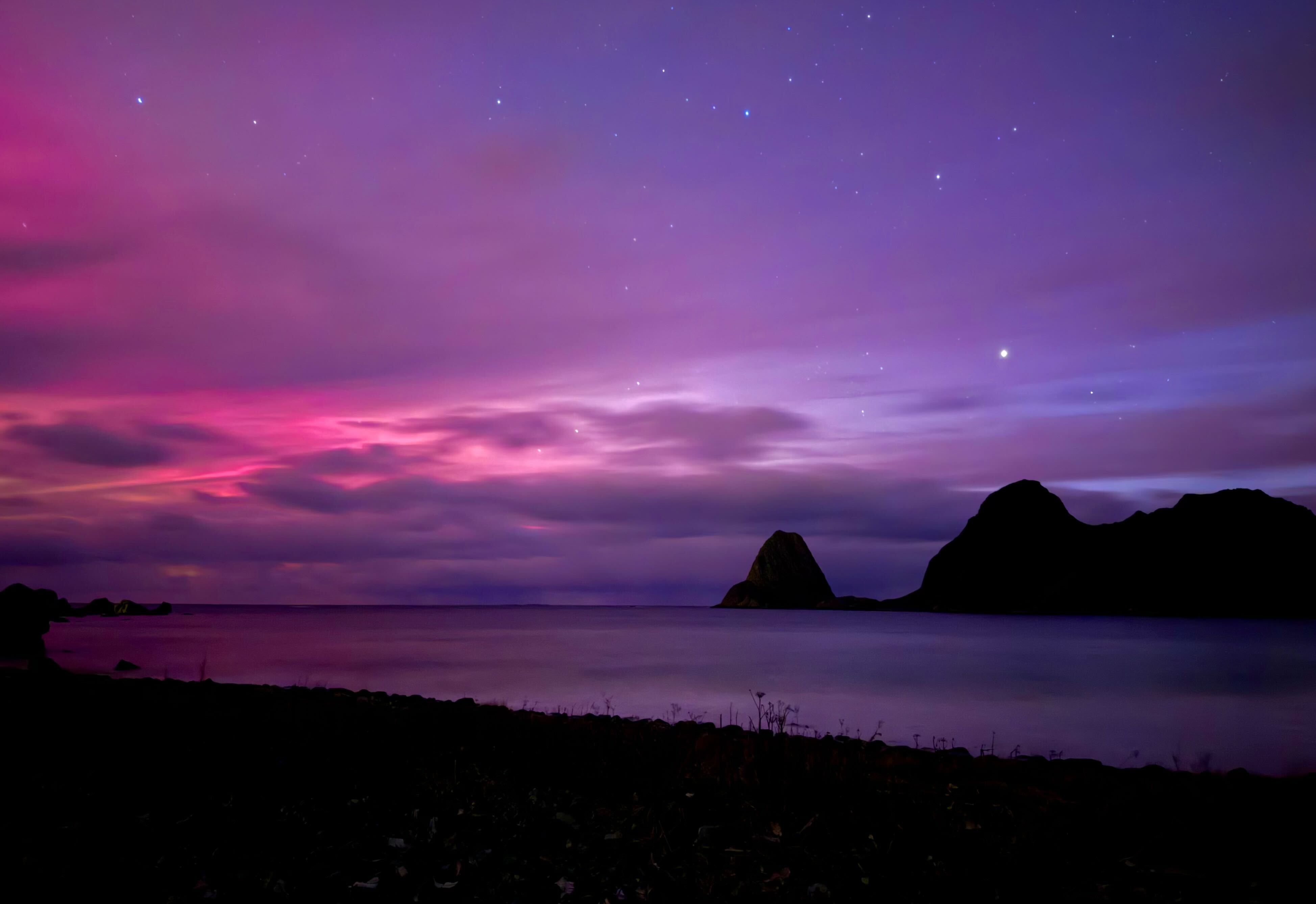 A purple and blue sky over a silver lake